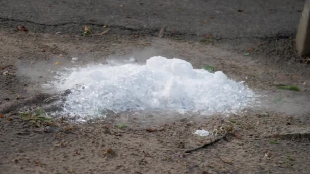 Pezzi di ghiaccio bianco si trovano su terra marrone e vapore il giorno di primavera — Video Stock