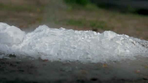 Pezzi di ghiaccio bianco si trovano su terra marrone e vapore il giorno di primavera — Video Stock