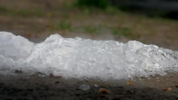 Pezzi di ghiaccio bianco si trovano su terra marrone e vapore il giorno di primavera — Video Stock