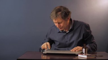 Gömlekli son sınıf öğrencisi masadaki laptopu alkolle temizliyor.