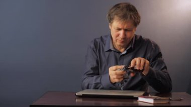 Tişörtlü olgun bir adam laptopu alkolle temizliyor.