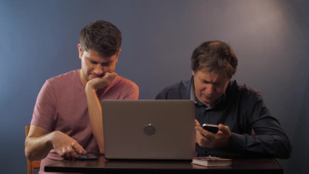 आदमी इंटरनेट पर सर्फ करता है जबकि पिता लैपटॉप और फोन का उपयोग सीखता है — स्टॉक वीडियो