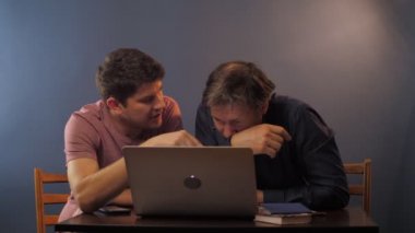 Bağlı babayla konuşan adam laptopta nasıl çalışacağını anlatıyor.