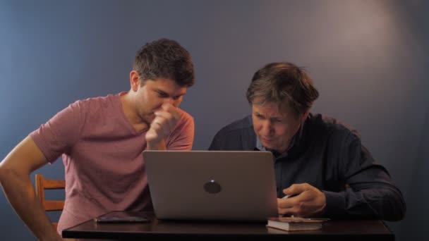 Happy man legt uit hoe het werk met laptop aan senior collega — Stockvideo