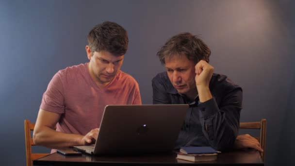 Seriöser Mann repariert Computer des älteren Vaters am Tisch — Stockvideo