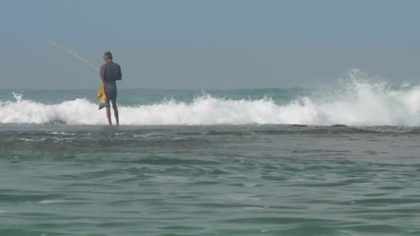 Пожилой сингальский человек рыбачит в бесконечном голубом океане с волнами — стоковое видео