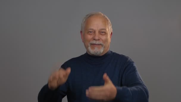 Щасливий пенсіонер в блакитному пуловері плескає руки і посміхається — стокове відео