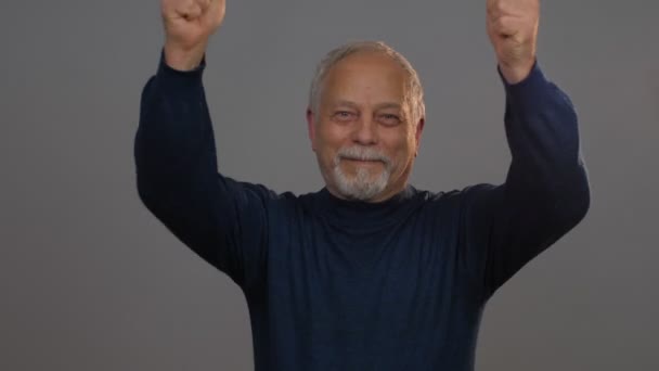 Opgewonden senior man heft handen en schudt tonen duim-up — Stockvideo