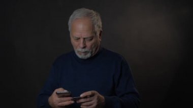 Akıllı telefondan banka kartı tutan konsantre emekliler.