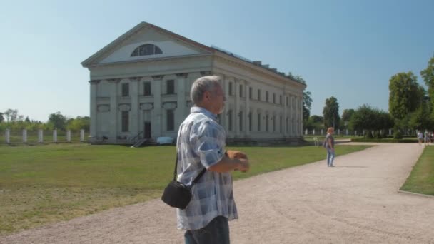 Uomo anziano tiene smartphone in mano contro il museo del maniero — Video Stock