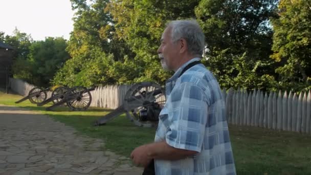 Pensioner detém câmera preta e tira foto no parque do museu — Vídeo de Stock