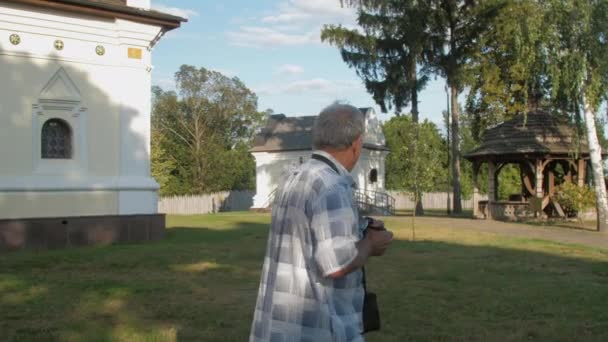 Pensionné tient caméra noire et prend des photos dans le parc du musée — Video