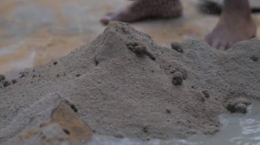 İnsan, metal kürekle hareket eden çimento ve suyu karıştırır.