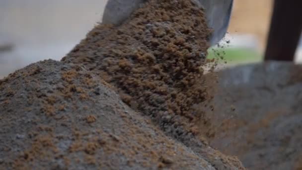 Persona mezcla cemento gris y arena amarilla con pala de madera — Vídeo de stock