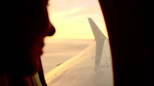 Mooie dame zit op raam stoel en observeert vliegtuig vleugel — Stockvideo