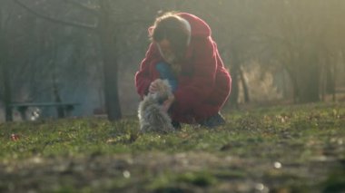 Kırmızı paltolu uzun saçlı bayan evcil hayvan tüylü köpek çayır üzerinde