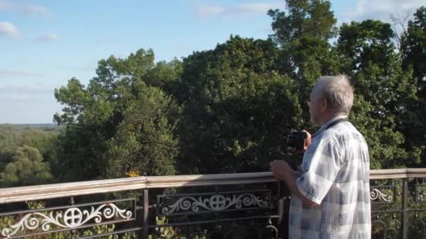 Vieil homme marche près de balustrade métallique contre la nature verte luxuriante — Video