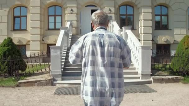Siwy emeryt przechadza się po pałacu z szerokimi schodami — Wideo stockowe