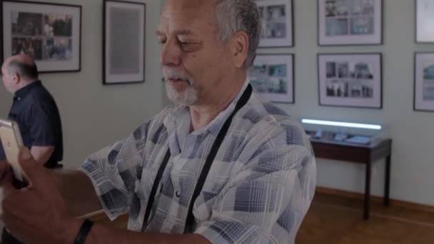 Пенсионер с седыми волосами фотографирует на стене — стоковое видео