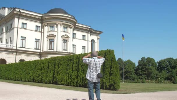 Gråhårig gammal man går längs grön park zon mot himlen — Stockvideo