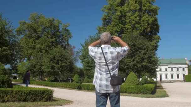 Pensioner holds phone and takes photo of museum castle — Stock Video