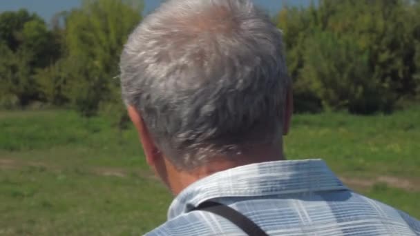 Active pensioner in jeans walks along green lawn actively — Stock Video