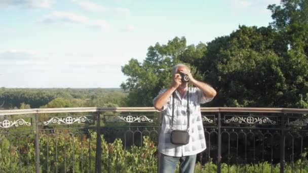 Old man walks near metal railing against lush green nature — Stock Video