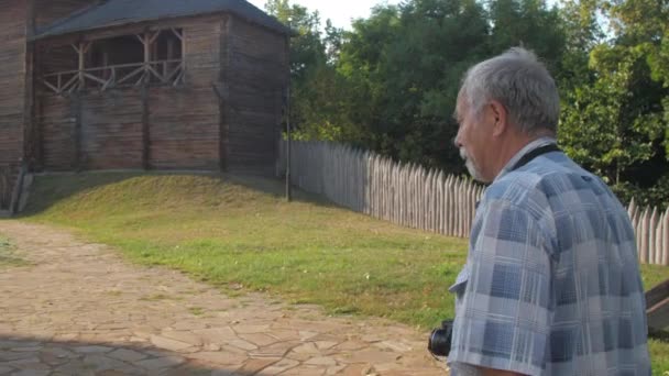 Retirado hombre con cámara en el cuello disfruta caminando por la calle — Vídeos de Stock