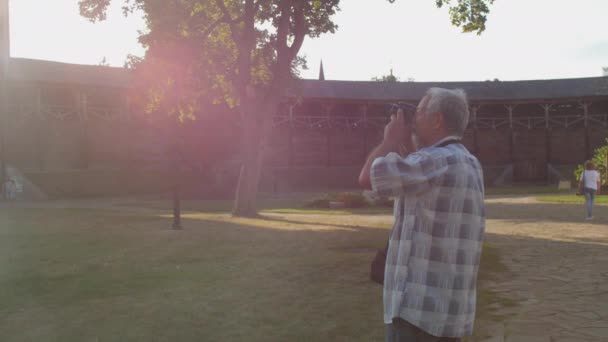 Starzec robi zdjęcia drewnianej twierdzy w muzeum na świeżym powietrzu — Wideo stockowe