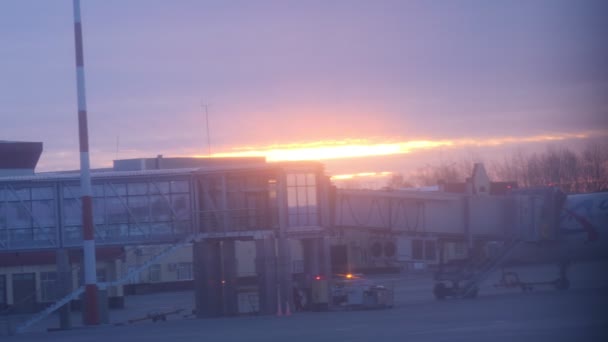 Zonsopgang tegen luchthaventerminal met telescopische gangway — Stockvideo