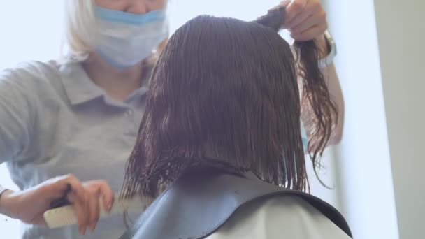 Mujer con máscara realiza corte de pelo utilizando instrumentos estériles — Vídeos de Stock