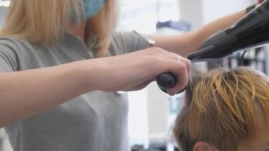 Kadın elleri modern kurutma makinesini tutuyor erkek saç stili yapıyor.