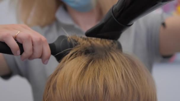 Kvinna i medicinsk mask torkar och volymer vackra hårstrån — Stockvideo
