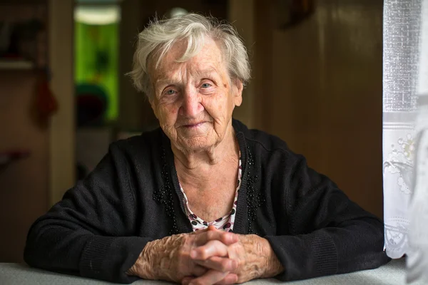 Oudere vrouw zittend aan tafel — Stockfoto