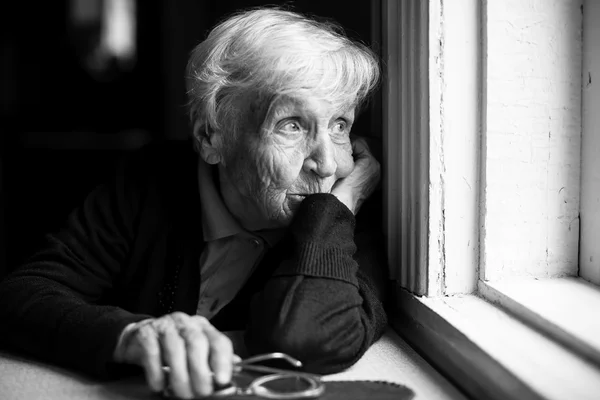 Donna anziana che guarda fuori dalla finestra — Foto Stock