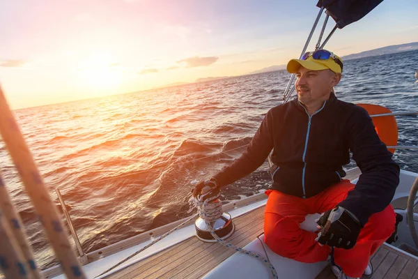 Homme assis sur le yacht pendant le coucher du soleil — Photo