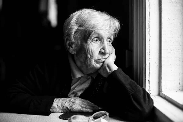 Femme âgée regardant par la fenêtre — Photo