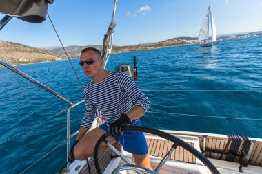 Adam yelkenli teknede dümen