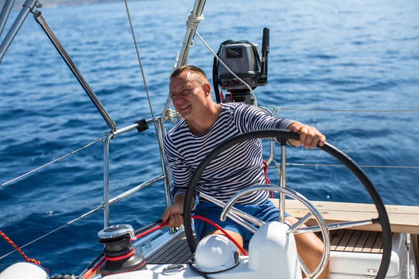 Jonge man aan het roer van de zeilboot — Stockfoto