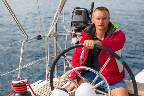 Skipper at the helm controls of a yacht