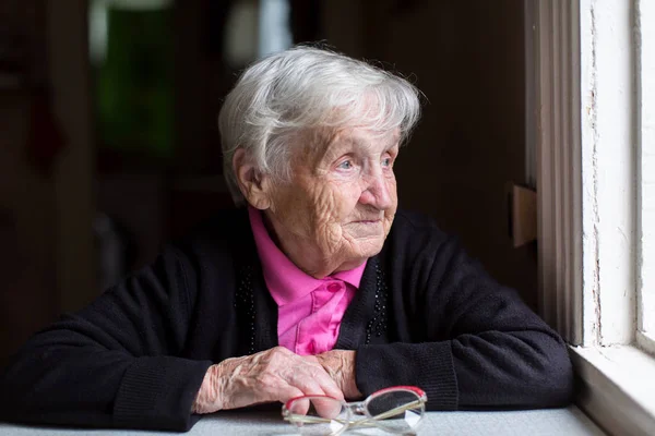 Elderly woman near window — Stock Photo, Image