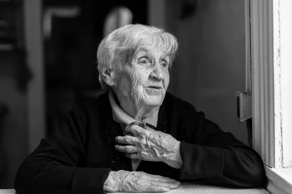 Elderly woman near window — Stock Photo, Image