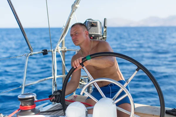 Man at helm of sail boat