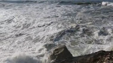 Büyük dalgalar taştan kumsala çarpıyor.