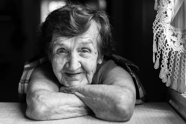 Oma zit in de buurt van het venster in de keuken. — Stockfoto