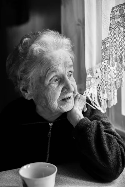 Mulher idosa com chá a uma mesa — Fotografia de Stock