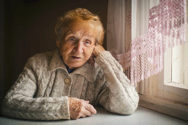 Ältere Frau sitzt ratlos da — Stockfoto