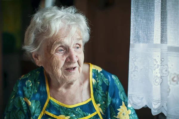 Ηλικιωμένη γυναίκα κοιτάζοντας από το παράθυρο. — Φωτογραφία Αρχείου