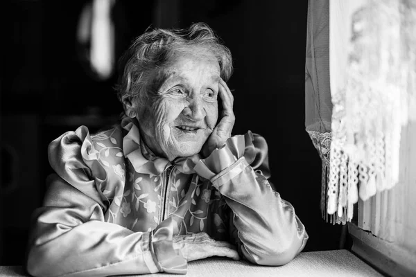 Starší dáma sedí u stolu — Stock fotografie