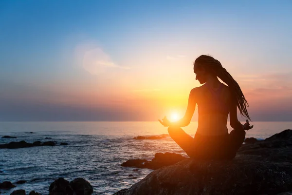 Kvinna utövar yoga vid solnedgången. — Stockfoto